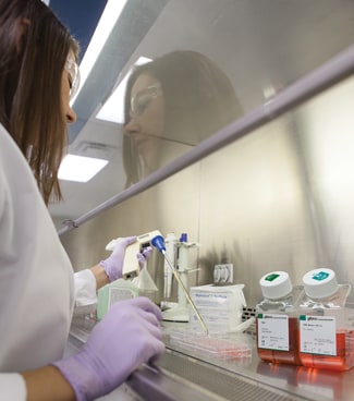 Gibco FBS usage A scientist pipetting Gibco FBS into media in a cell culture hood